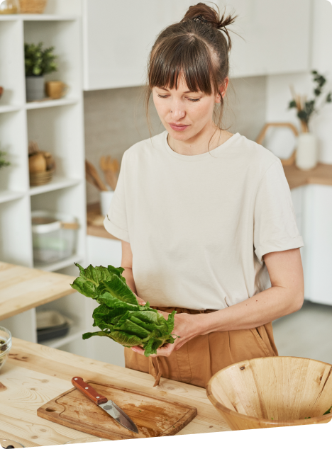 Woman holding fresh greens in a kitchen